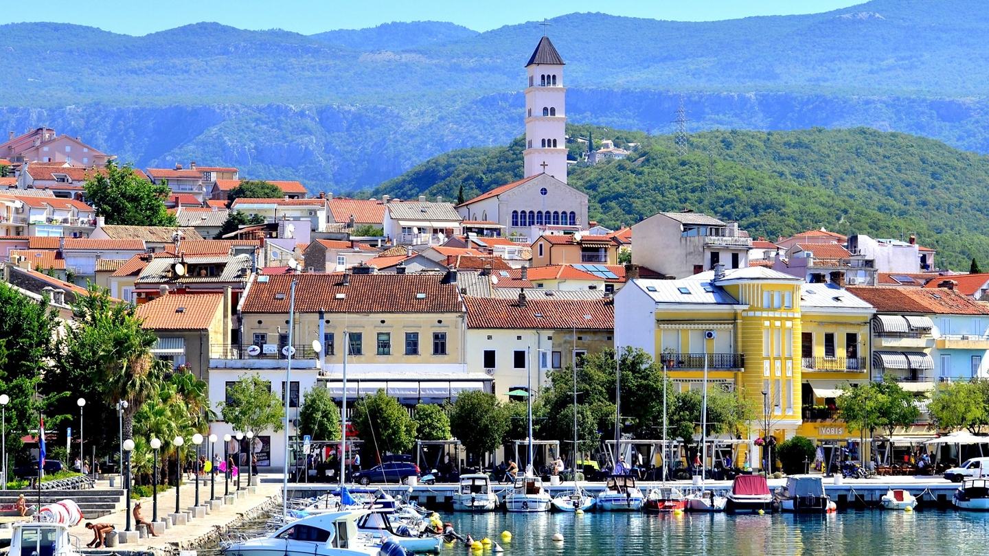 Der Hafen von Crikvenica, die Uferpromenade und der Glockenturm vor bewaldeten Hügeln