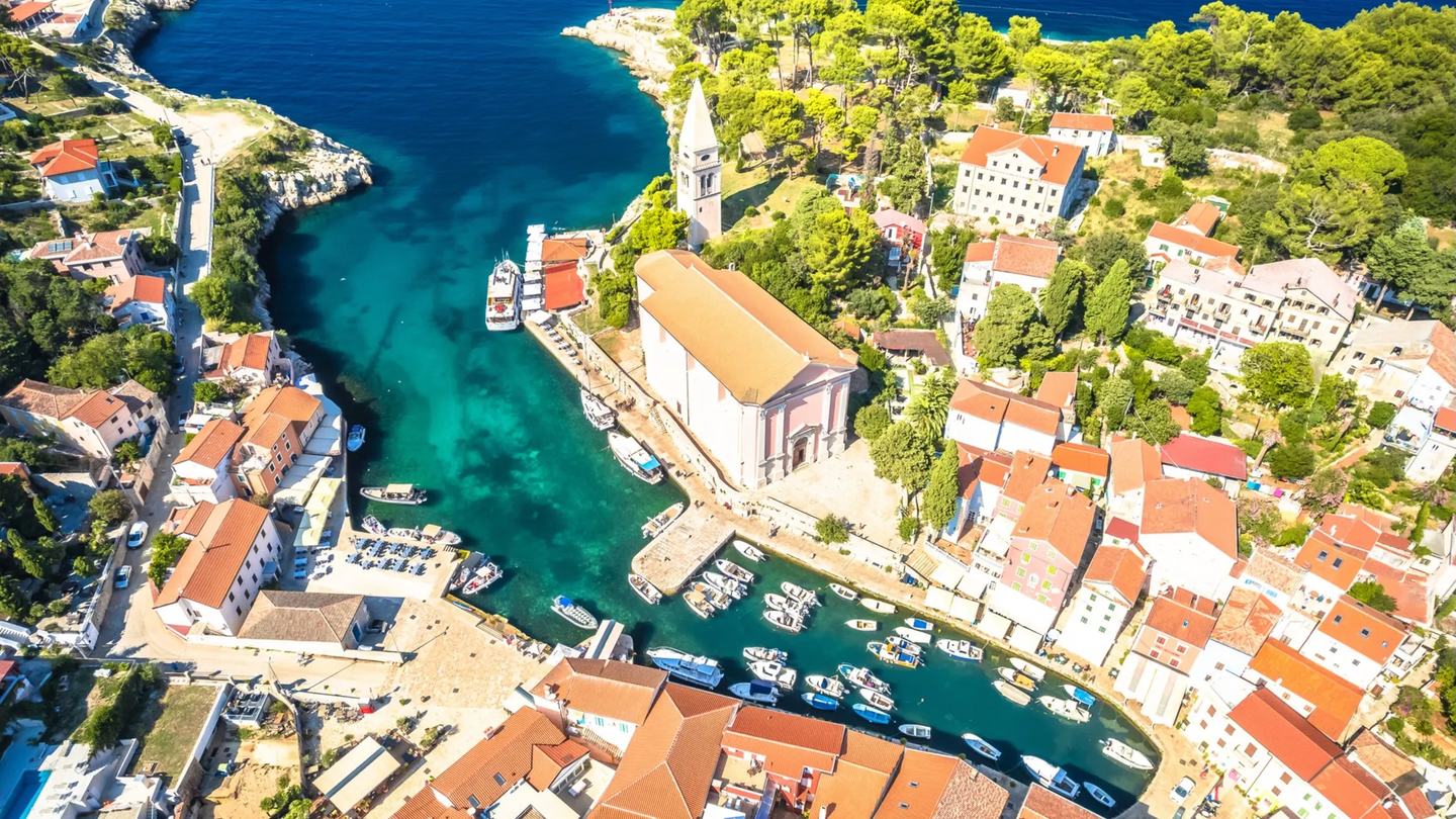 Veli Lošinj aus der Luft, die Kirche über einem schmalen Hafen voller kleiner Boote