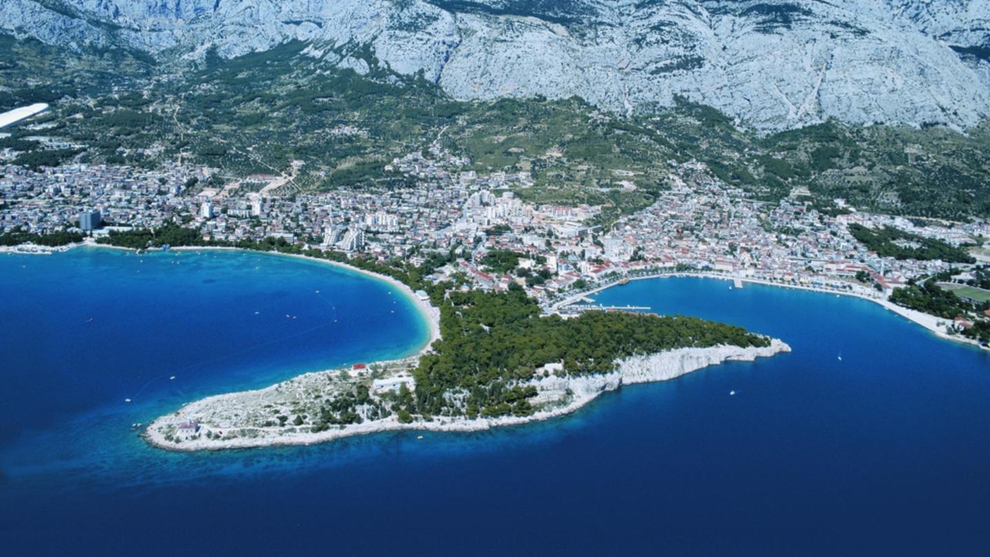 Makarska aus der Luft, die bewaldete Halbinsel Sveti Petar zwischen den beiden Buchten unter dem Biokovo