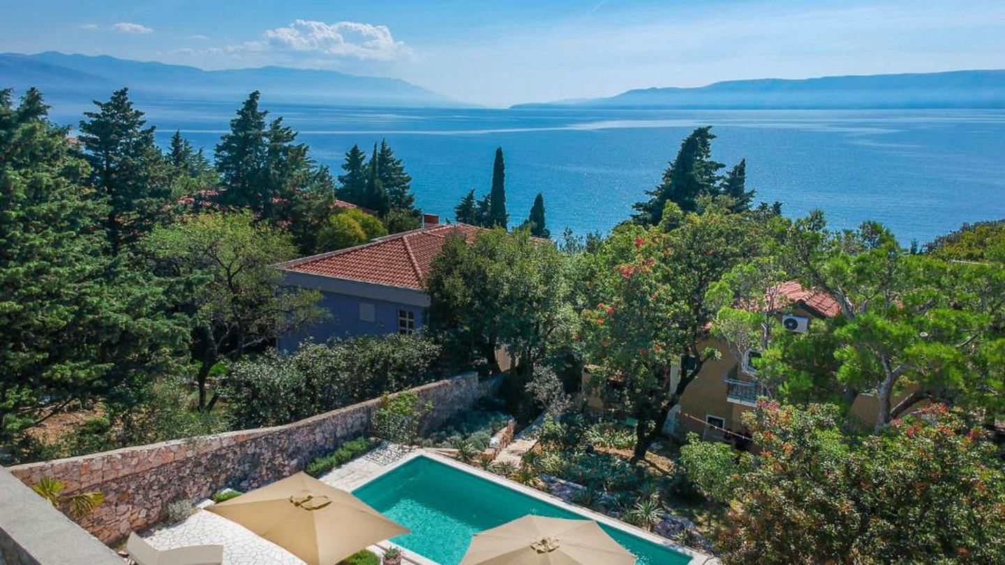 Ein Haus mit Pool über dem Meer bei Novi Vinodolski, Pinien und dahinter die Kvarner Bucht
