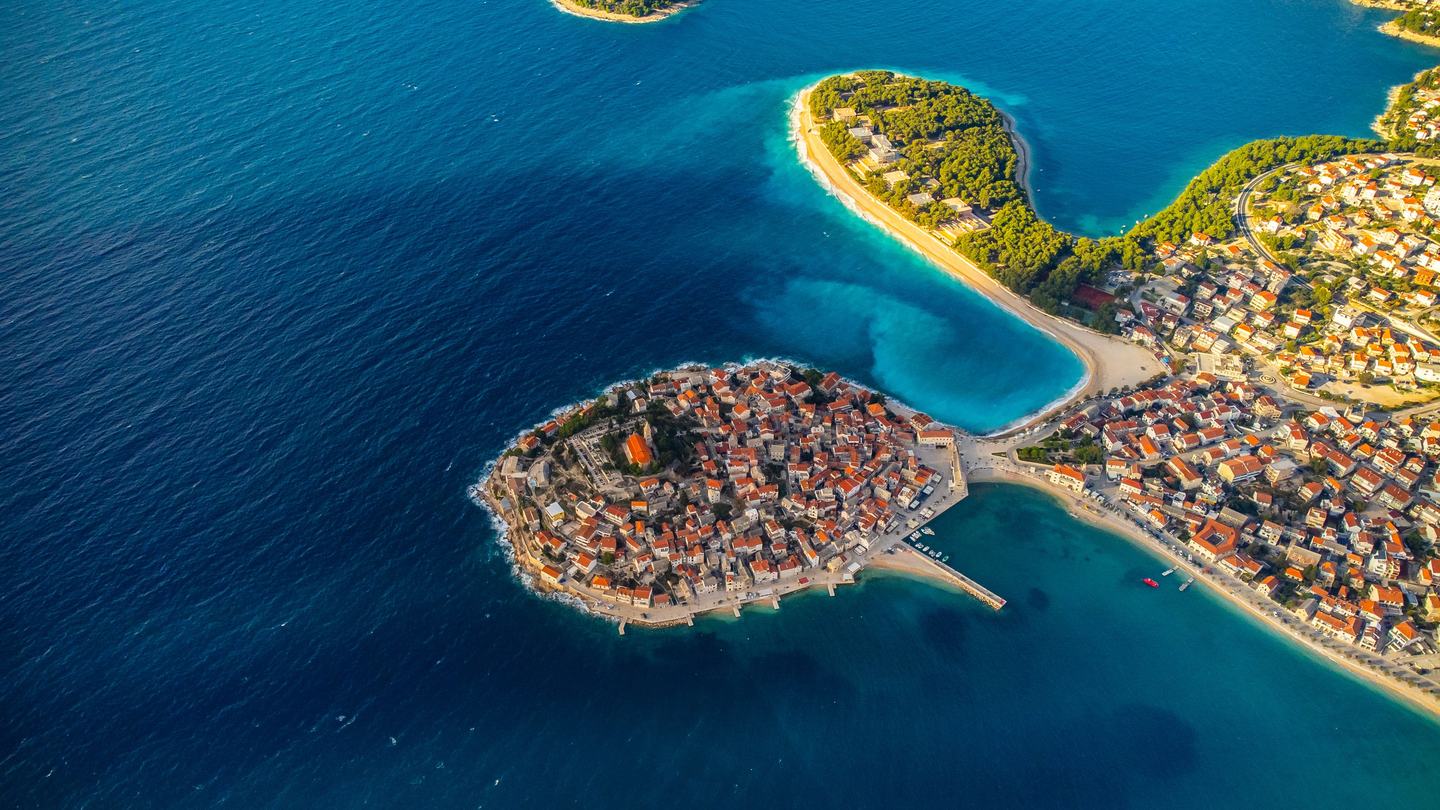 Die Altstadt von Primošten auf ihrer Halbinsel, aus der Luft mit dem Strand Raduča daneben
