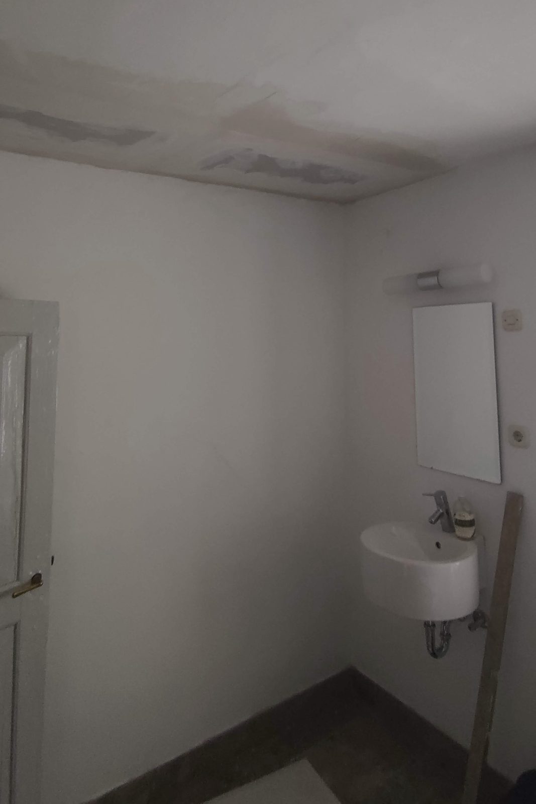 Dasselbe Badezimmer nach der Reparatur, Decke geschlossen, Boden frei von Schutt, Waschbecken und Spiegel wieder nutzbar